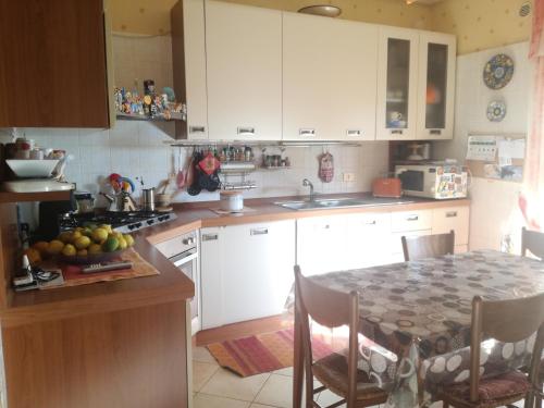 a kitchen with white cabinets and a table with a bowl of fruit at Ai piedi del Vulcano in Gravina di Catania