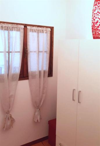 ペスキエーラ・デル・ガルダにあるApartment Elenaの白いカーテンとキャビネット付きのベッドルーム1室