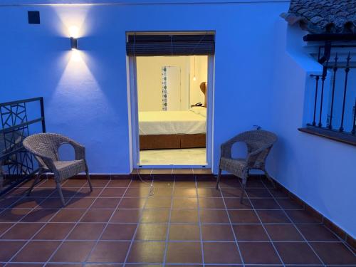 a room with two chairs and a bedroom with a bed at Hotel Don Miguel in Ronda