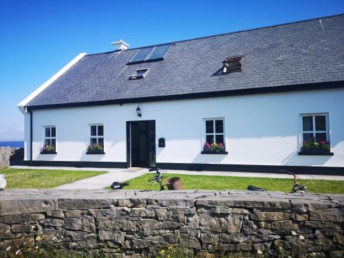 a white house with a stone wall in front of it at An Creagán Rooms in Inisheer