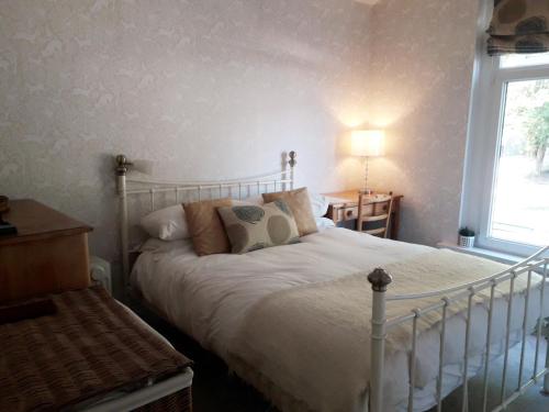 a bedroom with a white bed with pillows and a window at Tŷ Selah, Rugby Ave, Neath in Neath