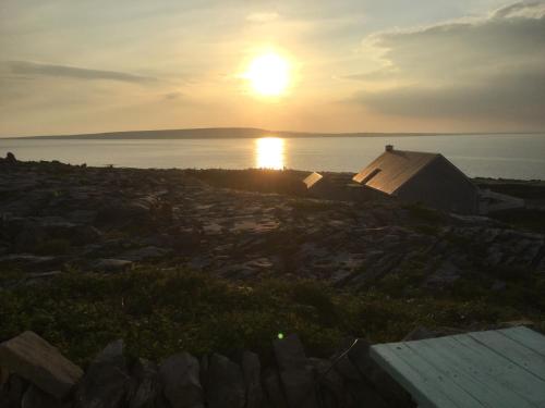 a sunset over a body of water with a tent at An Creagán Bed and Breakfast in Inisheer