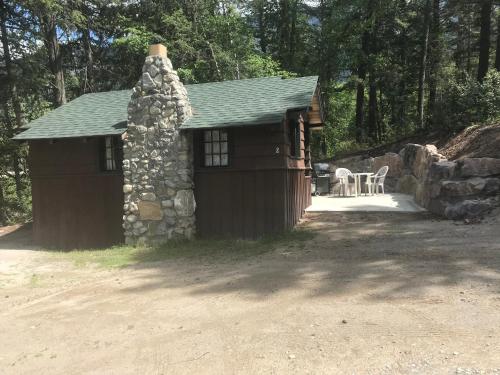 a log cabin with a stone wall and a table at Addison's Bungalows in Brisco