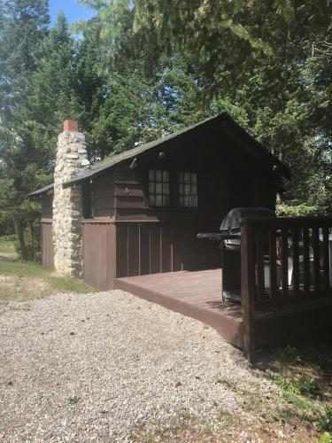a log cabin with a deck and a fireplace at Addison's Bungalows in Brisco