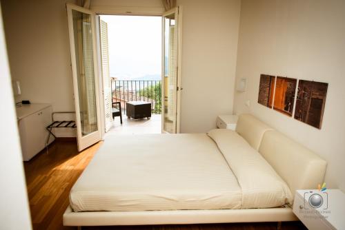 a bedroom with a large white bed and a balcony at La Castellana in Fosdinovo
