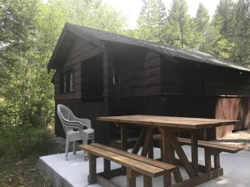 a picnic table and chairs in front of a black cabin at Addison's Bungalows in Brisco