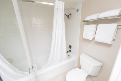 a white bathroom with a shower and a toilet at Ocean Coast Hotel at the Beach Amelia Island in Fernandina Beach