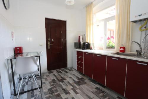 a kitchen with red cabinets and a table and a window at Union Square Apartment 2 by NUX in Cluj-Napoca
