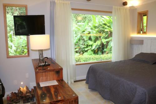 a bedroom with a bed and a television and a window at Auberge Suisse Pousada in Nova Friburgo