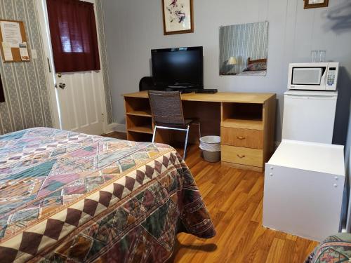 a bedroom with a bed and a desk with a microwave at Regent Motel in Saint John