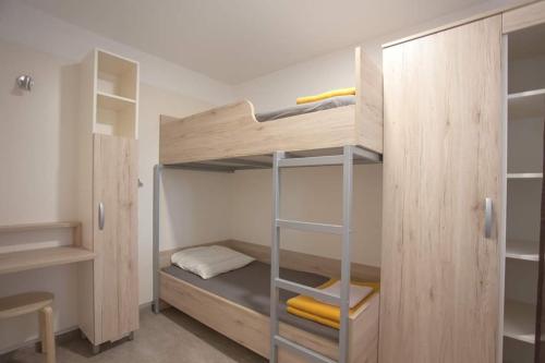 a small bedroom with a bunk bed with a ladder at Bungalov comfort - 100 m from the beach in Premantura