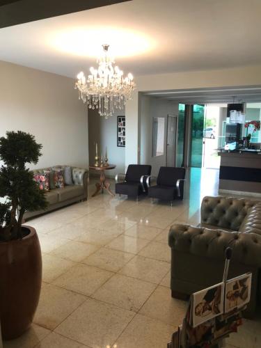 a living room with couches and a chandelier at Oásis Hotel in Araguaína