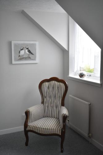 a chair sitting in a room with a window at Monturpie Guest House in Kirkton of Largo