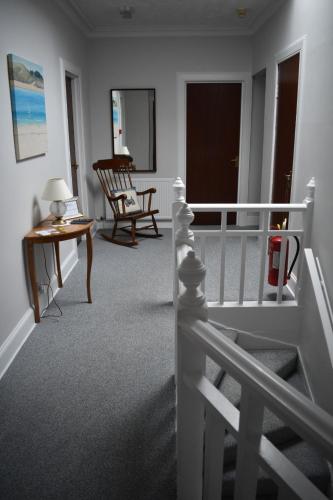 a room with a staircase and a table and a chair at Monturpie Guest House in Kirkton of Largo