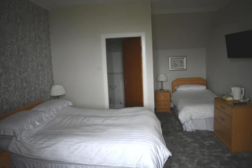 a hotel room with two beds and a television at Monturpie Guest House in Kirkton of Largo