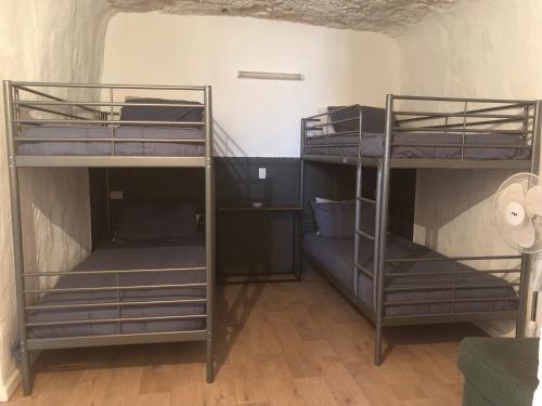 Cette chambre comprend 2 lits superposés et du parquet. dans l'établissement The Blacklighters Opal Retreat-Undergound, à Coober Pedy