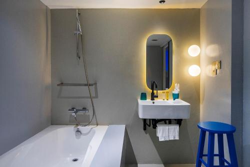 a bathroom with a tub and a sink and a mirror at Hi Hotel in Singapore