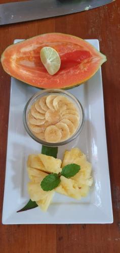 Hidden Cove Eco Retreat في لوجنفيل: طبق أبيض مع وعاء من الطعام وقطعة من الفاكهة