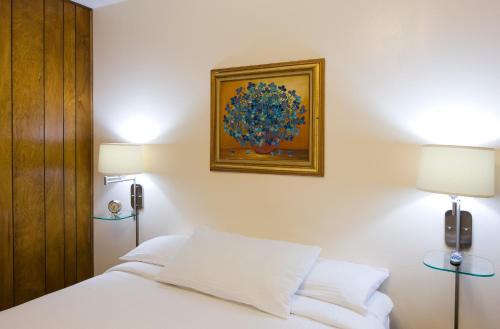 Un dormitorio con una cama blanca y una pintura en la pared en Sunset Motel Moriarty, en Moriarty