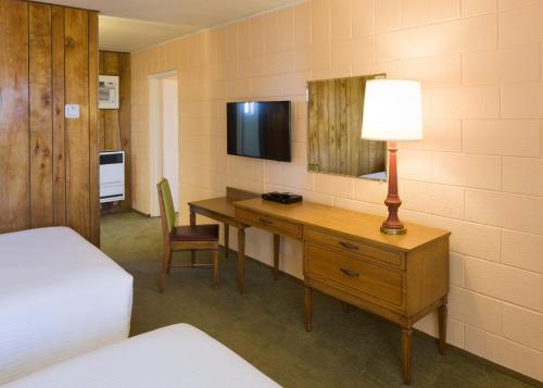 a room with a desk with a lamp and a television at Sunset Motel Moriarty in Moriarty