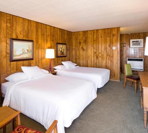 two beds in a room with wooden walls at Sunset Motel Moriarty in Moriarty