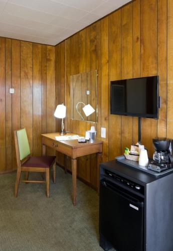 a room with a desk and a television and a desk with a chair at Sunset Motel Moriarty in Moriarty