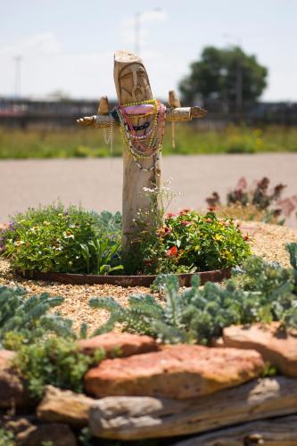 a statue in a garden with flowers and plants at Sunset Motel Moriarty in Moriarty