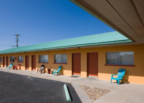 a building with blue chairs sitting outside of it at Sunset Motel Moriarty in Moriarty