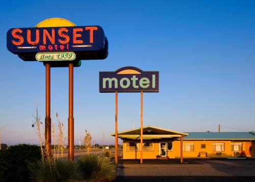 a motel with two signs in front of a motel at Sunset Motel Moriarty in Moriarty