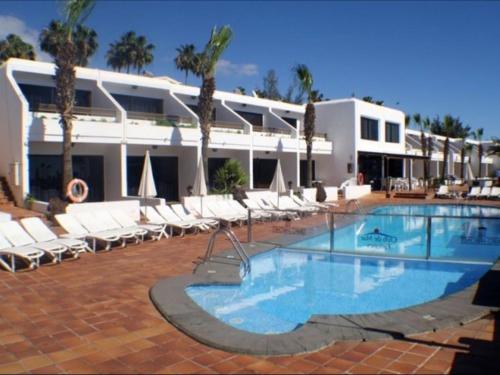 ein großer Pool mit Liegestühlen und ein Hotel in der Unterkunft Bonito y espacioso apartamento al lado de la playa. in Tías