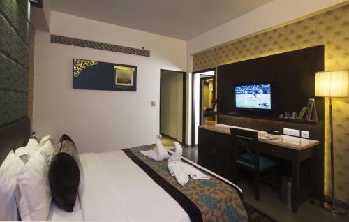 a hotel room with a bed and a desk and a television at Regenta Orko's Haridwar, Motichur, 10 min from Har ki Pauri in Haridwār