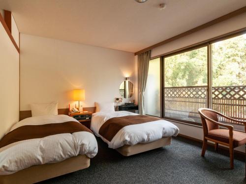 a hotel room with two beds and a balcony at Kikuchi Grand Hotel in Kikuchi