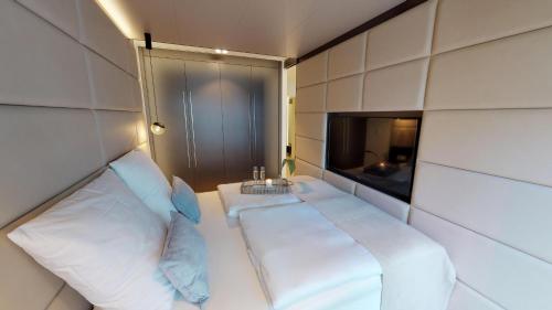 ティメンドルファー・シュトラントにあるWhite Pearl Apartment 1.14のベッド1台とテレビが備わる小さな客室です。