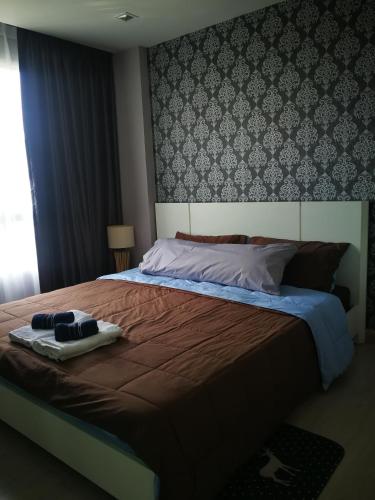 a bedroom with a large bed with a brown comforter at Diamant Modern Room Condominium Resort in Chiang Mai