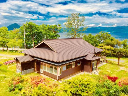 a small house with a roof on a field at 自然の中の古民家ゲストハウスちゃいはな庵 Organic county style classic house Chaihana an in Lake Toya