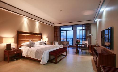 a bedroom with a large bed and a living room at Kangte Wangfu Hotel of Resort And Conference in Sanya