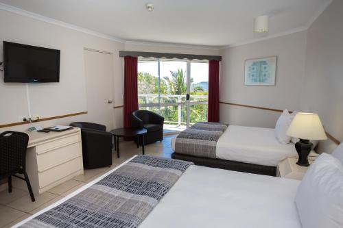 a hotel room with two beds and a television at Ocean International Hotel in Mackay