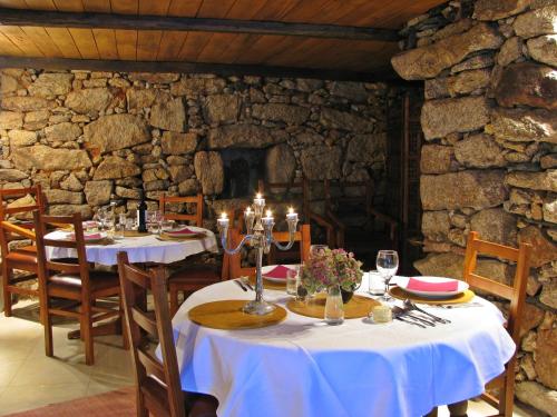 a dining room with two tables and a stone wall at A Lagosta Perdida in Montezinho