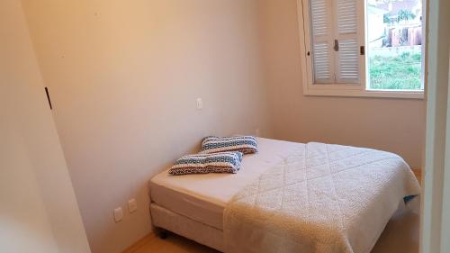 ein Schlafzimmer mit einem Bett mit zwei Kissen darauf in der Unterkunft Apartamento em condominio fechado Bento Goncalves in Bento Gonçalves