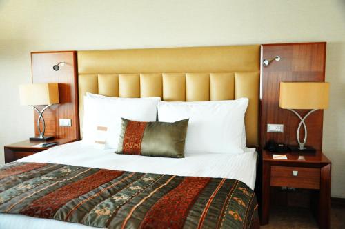 a large bed in a hotel room with two lamps at Mövenpick Hotel Izmir in Izmir
