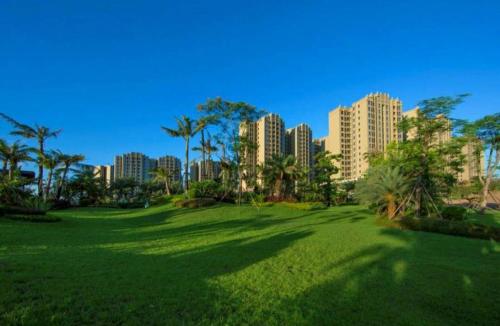 a green park with palm trees and tall buildings at Green Collection Care Hotel (24 Hours Free Transfer from Meilan Airport/Railway Station) in Haikou