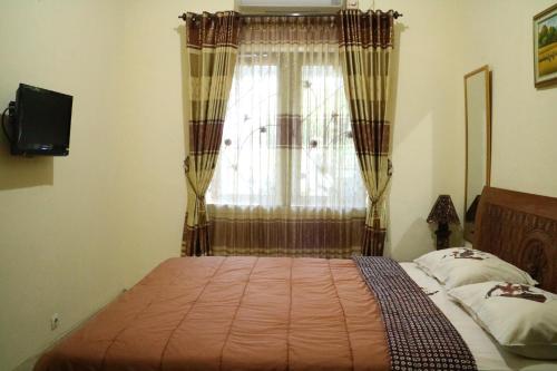 a bedroom with a bed and a window with curtains at The Homey Rooms and Tours in Yogyakarta