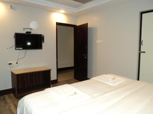 um quarto com uma cama e uma televisão na parede em Mani's residency em Madurai