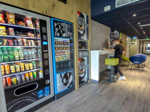 a woman is sitting at a counter in a soda machine at ibis budget Brignoles Provence in Brignoles