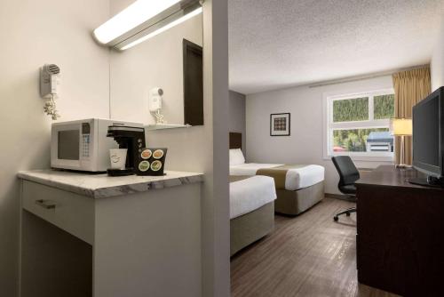 a hotel room with a bed and a desk with a microwave at Travelodge by Wyndham Blairmore in Blairmore