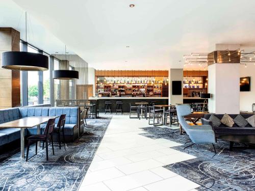 a restaurant with tables and chairs and a bar at Mercure Bristol Holland House in Bristol