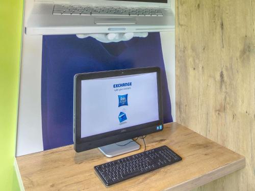 a computer monitor and keyboard on a desk with a laptop at ibis budget Brignoles Provence in Brignoles