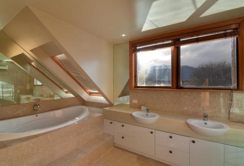 baño con 2 lavabos, bañera y ventana en Manata Homestead & Lodge en Queenstown