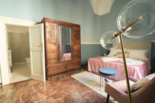 a room with a bed and a chair and a mirror at PALAZZO FORLEO Luxury Apartment - TREB Collection in Lecce