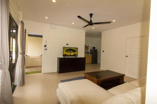 a living room with a couch and a ceiling fan at Aussieland Bungalows in Lamai